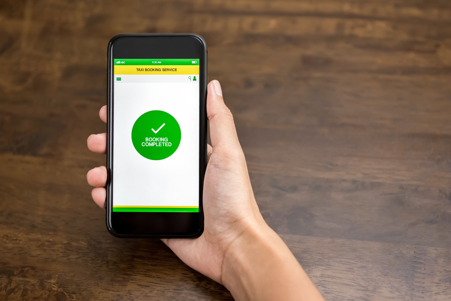 Hand holding smartphone showing confirmation text in taxi reservation application